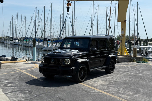 Black SUV parked at a marina with boats in the background