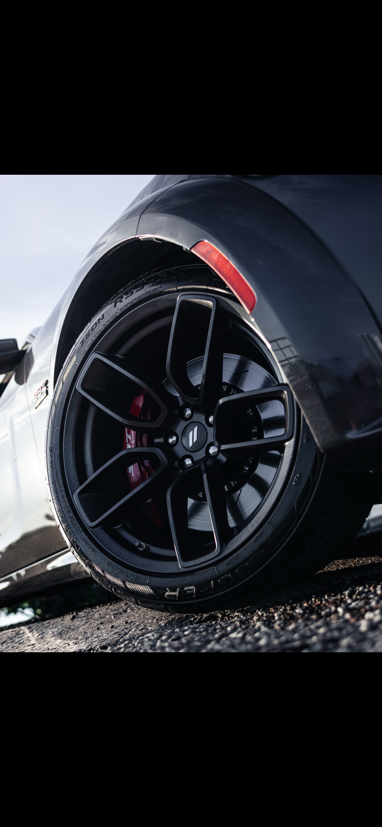 Close-up of a black car wheel with red accents on a road.