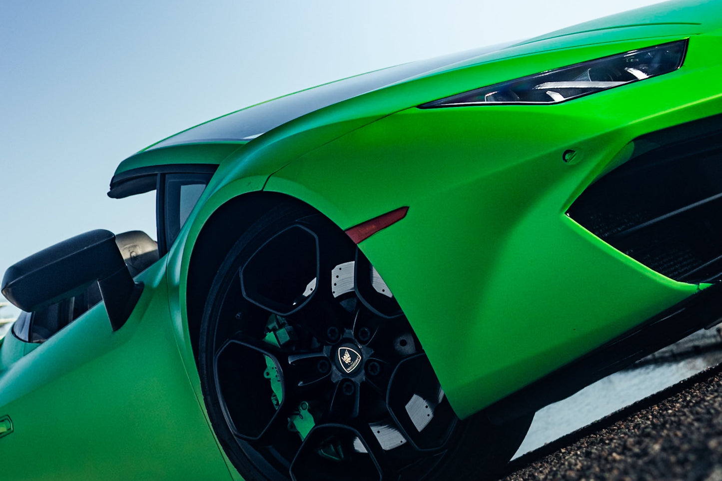 Alt text: "Close-up view of a vibrant green sports car showcasing its sleek design, hexagonal black alloy wheels, and aerodynamic lines, perfect for luxury car enthusiasts seeking high-performance vehicles."