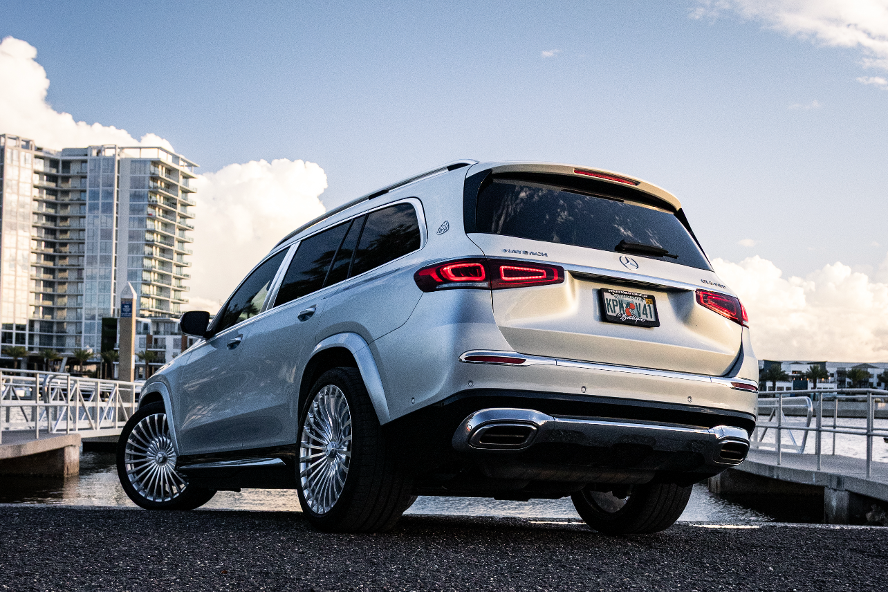 alt text: "Luxury silver SUV parked by the waterfront, showcasing sleek design and modern features against a scenic background with blue skies and clouds. Perfect for those seeking comfort and style in their next vehicle purchase."