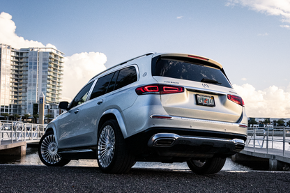 alt text: "Luxury silver SUV parked by the waterfront, showcasing sleek design and modern features against a scenic background with blue skies and clouds. Perfect for those seeking comfort and style in their next vehicle purchase."