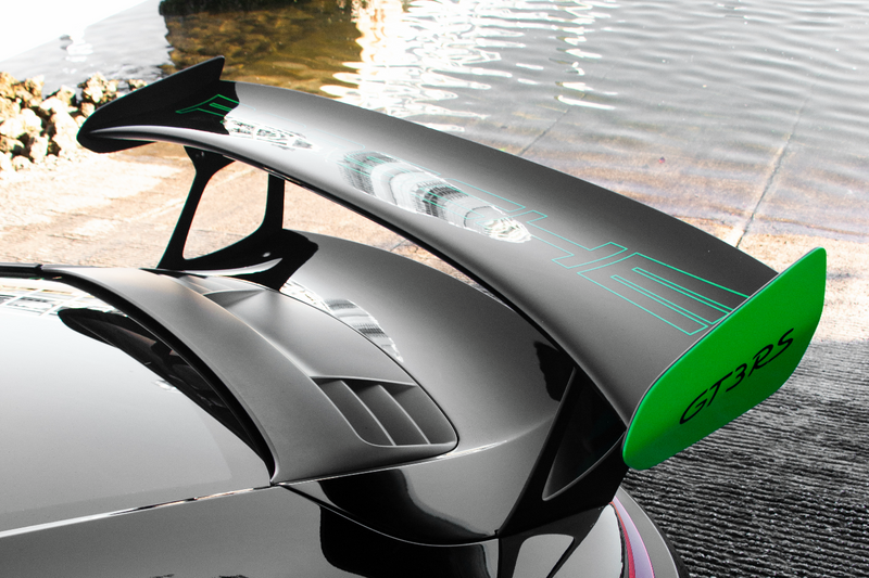 Car spoiler with green accents on a vehicle, blurred background