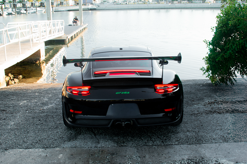 Black sports car with a red stripe on a bridge