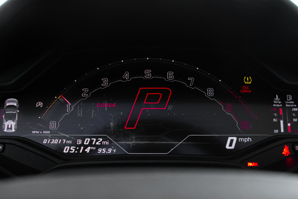 Car dashboard with digital display showing a red 'P' in a dark setting