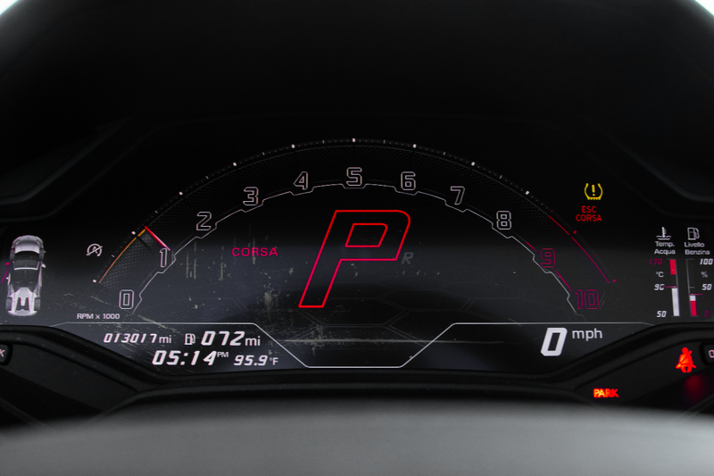 Car dashboard with digital display showing a red 'P' in a dark setting