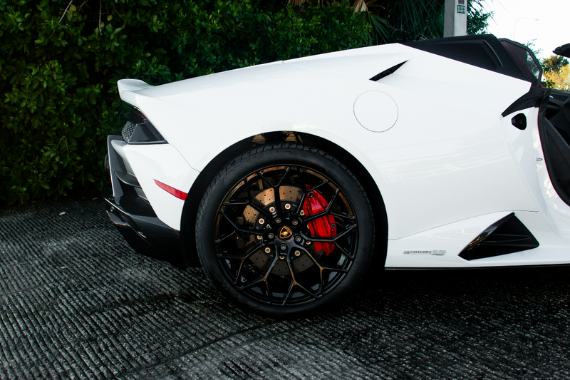 White sports car with black rims on a textured surface