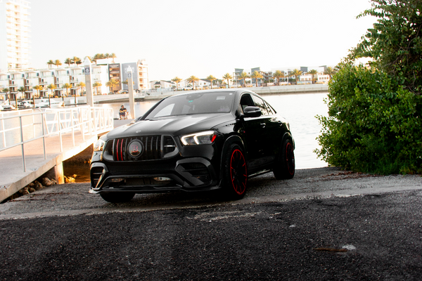 Black car parked on a road with a scenic background