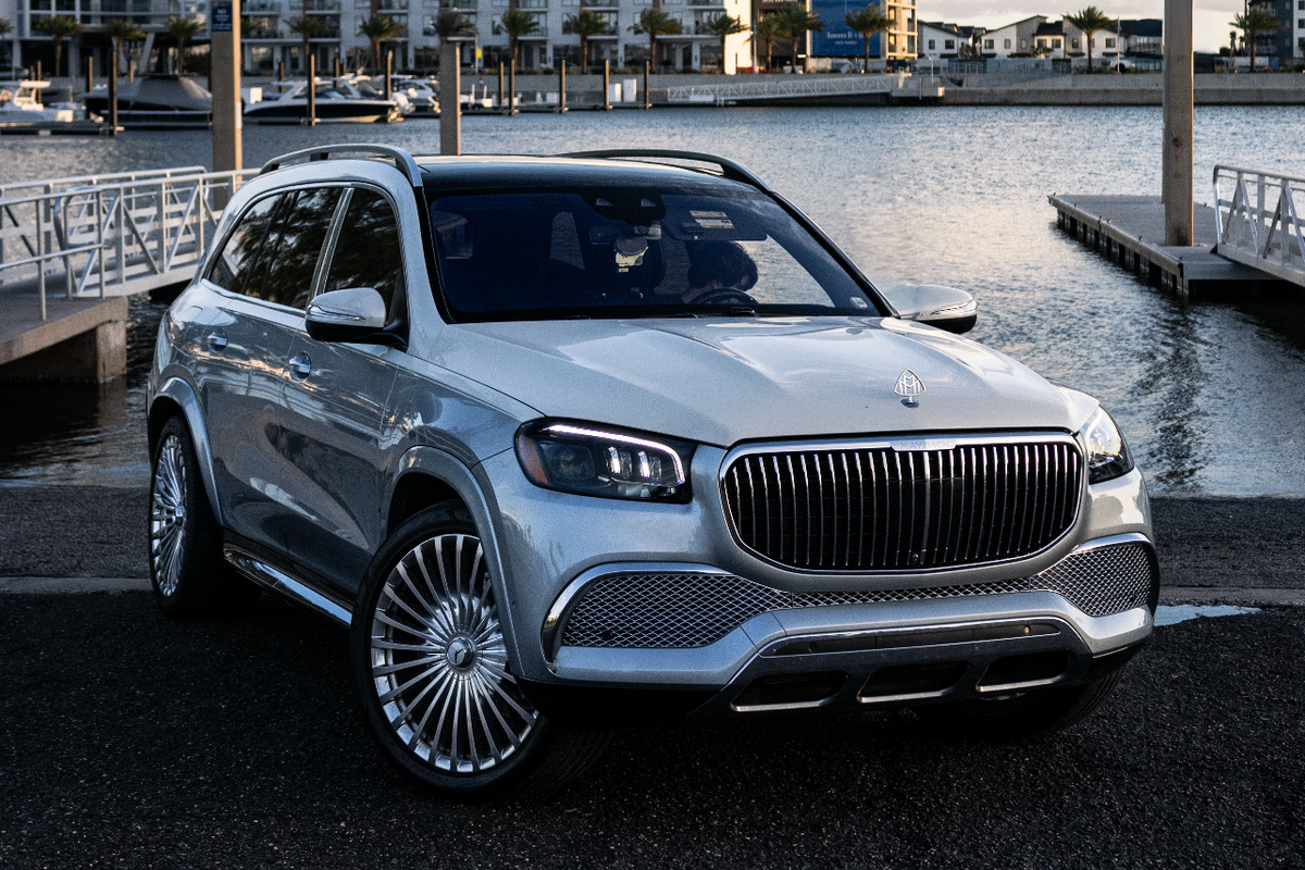 Luxury car parked by a waterfront with buildings in the background