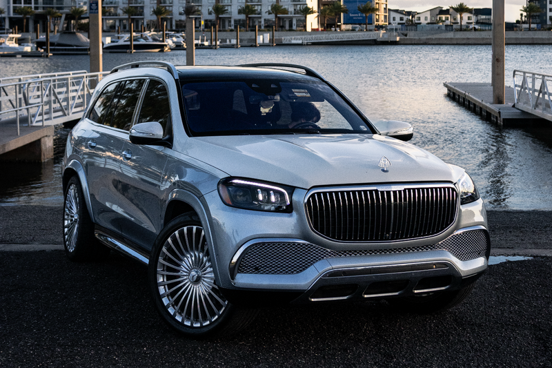 Luxury car parked by a waterfront with buildings in the background