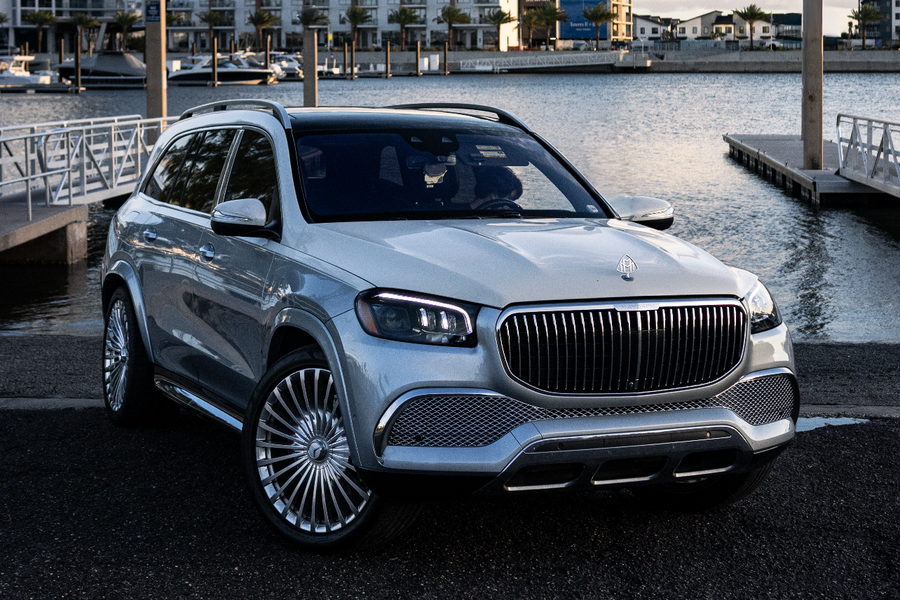 Luxury car parked by a waterfront with buildings in the background