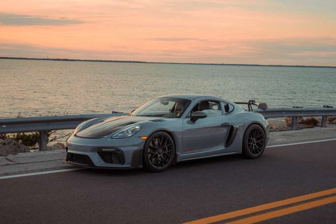 Sports car on a road with a scenic sunset over water